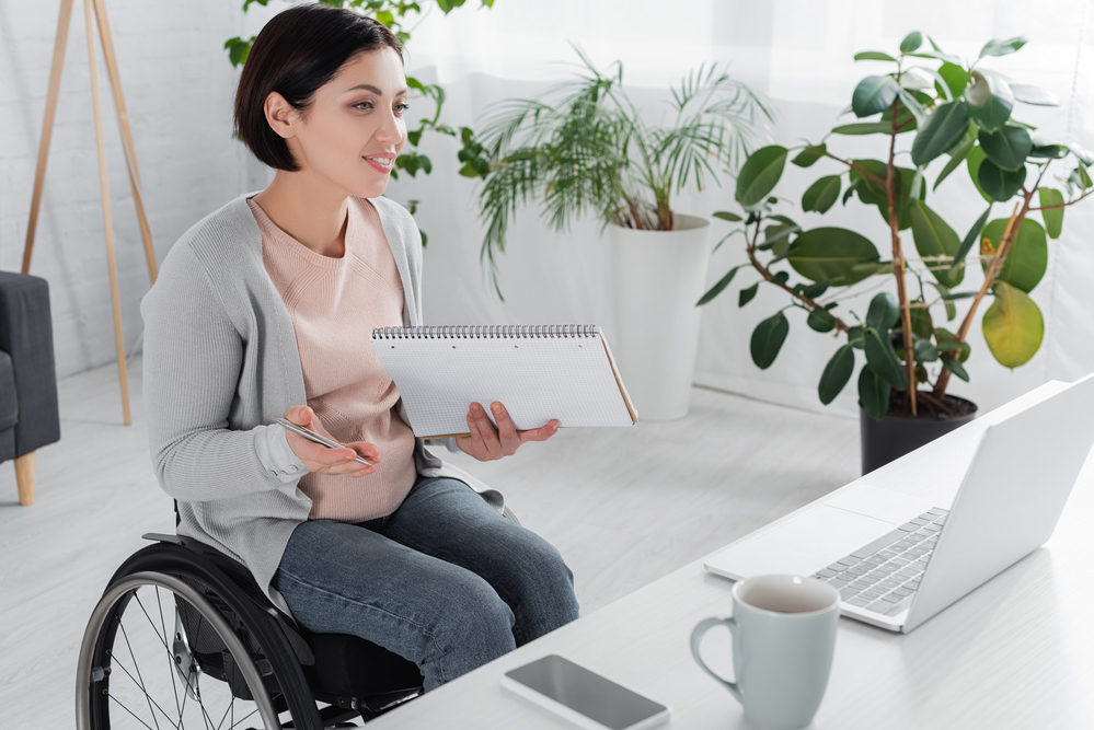 Huge List of Work at Home Jobs For Reliable Income | Think Daily 5 Woman in s wheelchair working from home